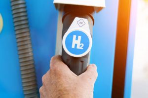 Man holds a fuel dispenser with hydrogen logo on gas station. h2 combustion engine for emission free eco friendly transport.