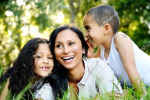 Happy family outdoors on the grass in a park. mom and two children smiling