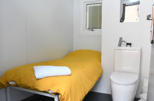 The interior of a nap pad with a bed, towel, toilet