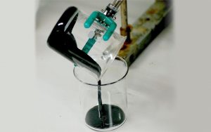 Electrically conductive polymer polyaniline being poured between flasks in a laboratory.