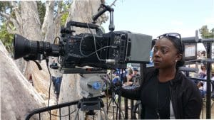 Black woman operating camera equiptment wearing a black outfit.