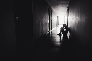 Silhouette of Sad Grieving Depressed man sitting head in hands on the floor.