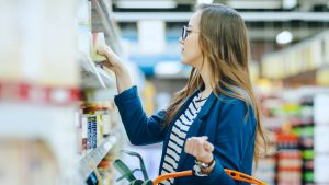 young woman examines labels on groceries while shopping