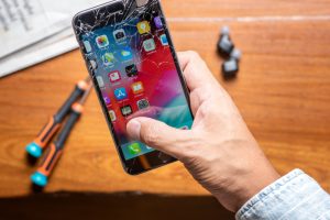 Man holding a broken iPhone and tools