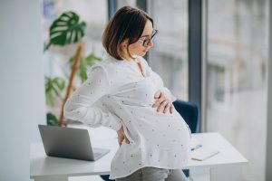 Young pregnant business woman at the office