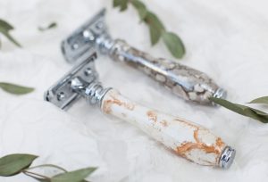 metal safety razor for shaving with an epoxy handle on a white background with greens