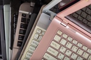 six laptops in a variety of colors stacked and fanned out one on top of the other