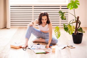 woman sits on the floor making a vision board or anti vision board