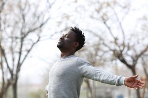 young Black man stretches and breathes outside