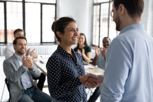 a woman is congratulated by a colleague at work