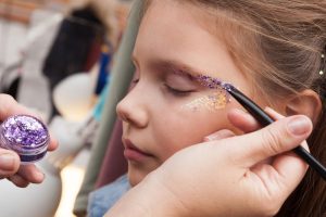 Girl gets face painted with glitter