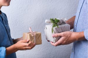 Two people exchange sustainably wrapped gifts