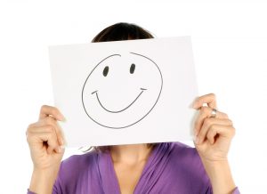 Woman holding a paper with a smiley on her face.