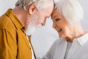 Elderly couple joining heads to signify a happy relationship.