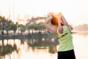 Young Asian woman stretching in front of a lake