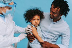 Toddler held by her father is getting vaccinated by healthcare provider to prevent corona virus outbreak