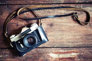 Old retro camera on vintage wooden boards abstract background.