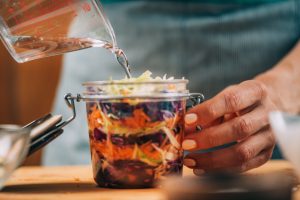 person prepares to preserve shredded vegetables in a mason jar