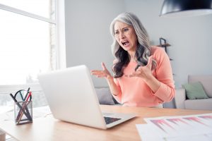 Woman wearing a pink shirt stressed and overwhelmed at writing task.