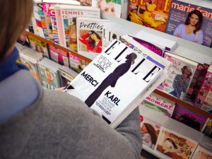 Person holding ELLE magazine at newsstand