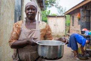 Kenyan woman stands outside with pot