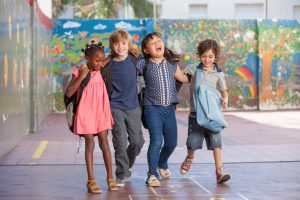 four diverse and happy kids embrace each other