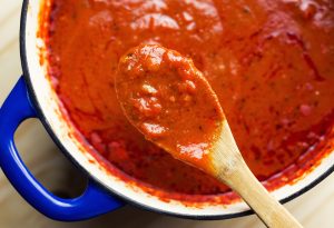 Overhead view of savory marinara, slow cooked all day in an enamel coated cast iron Dutch oven.