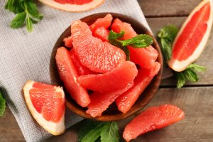 Juicy grapefruit pieces with fresh mint in a bowl, close up.