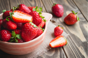 Full bowl of strawberries lying on a wooden table