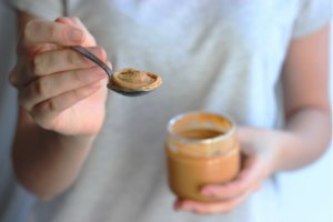 someone spooning out peanut butter from the jar