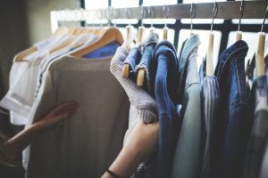 Person looking through clothes in a store when shopping.