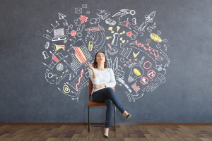 woman sits in front of chalkboard with imaginative drawings