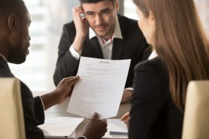 nervous interviewee sits in front of black business man and white business woman