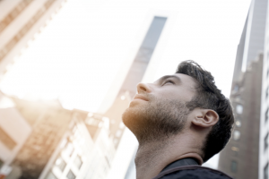 man looks up at city skyscrapers