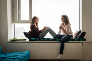 mother and daughter have a conversation by the window